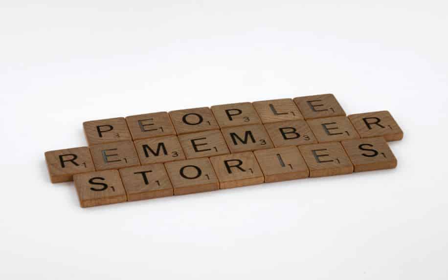 Scrabble game pieces spelling out the phrase "people remember stories"