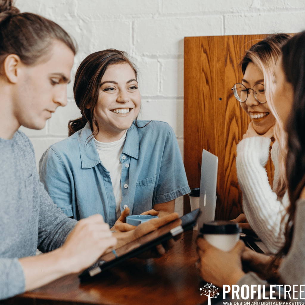 An image of friends laughing while looking at a phone